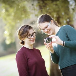 girls holding a small camera